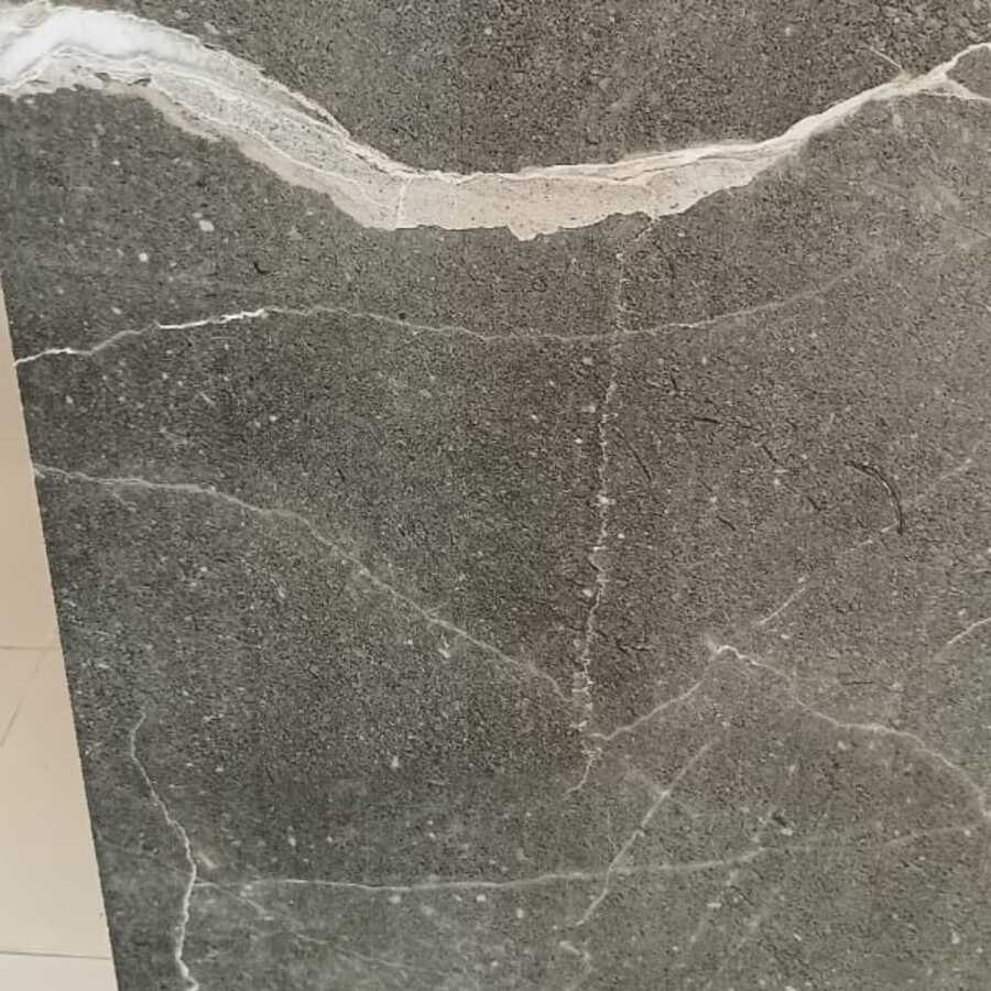 Close-up of a grey stone-look porcelain tile showing low-reflection texture